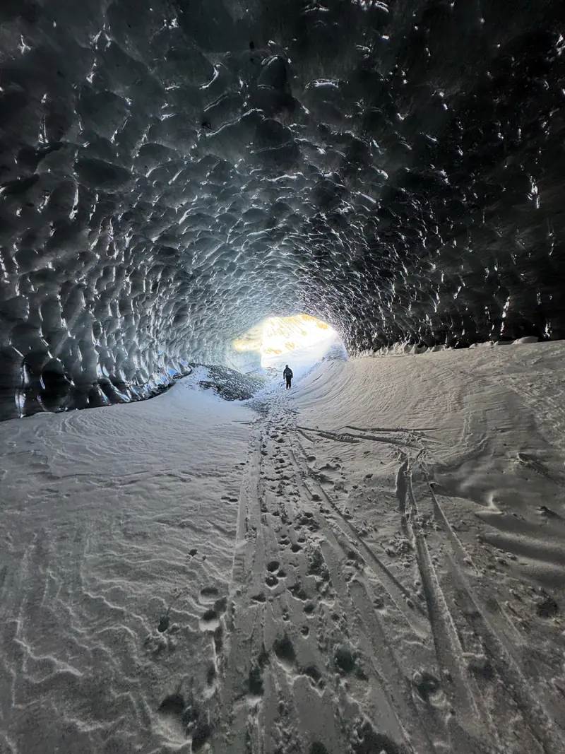 Skispuren führen aus einer Gletscherhöhle ins Tageslicht
