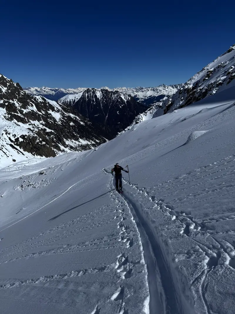 Ein Skitourengeher folgt einer Aufstiegsspur in einem hochalpinen Tal