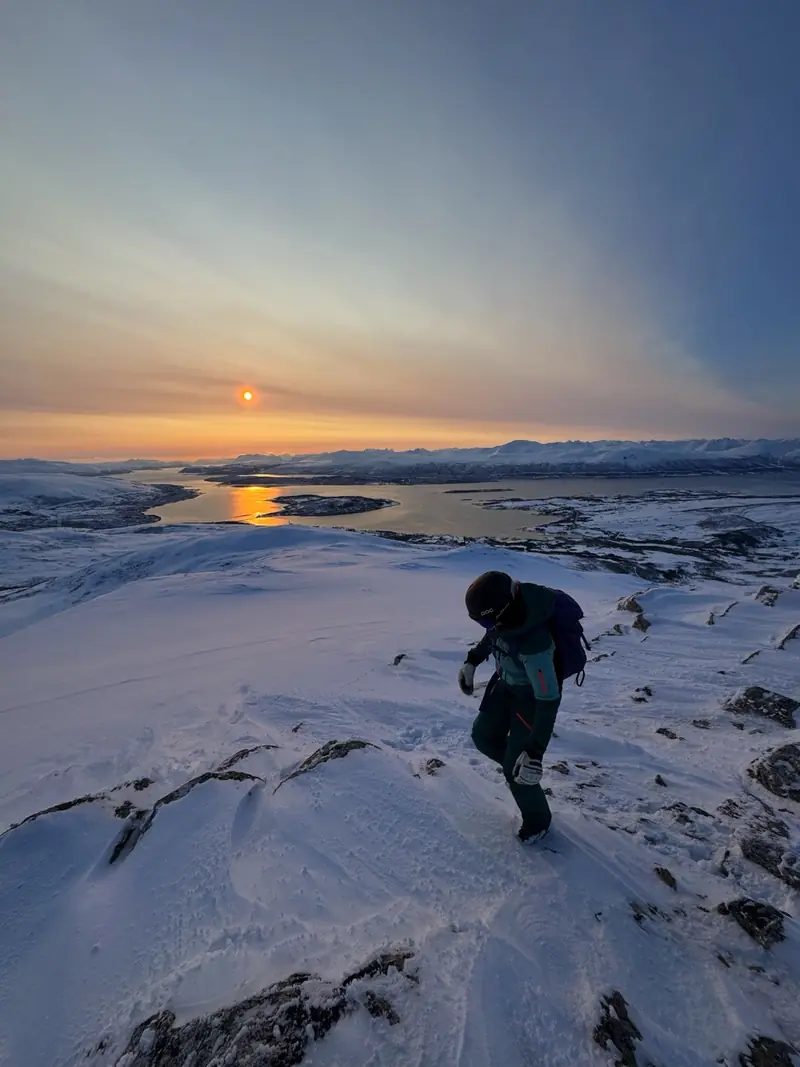 Ein Berggänger auf Fels und Schnee bei Sonnenaufgang über dem Nebelmeer
