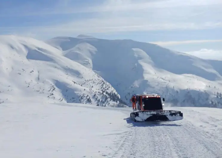 Un snowcat montant entre des montagnes enneigées en Géorgie