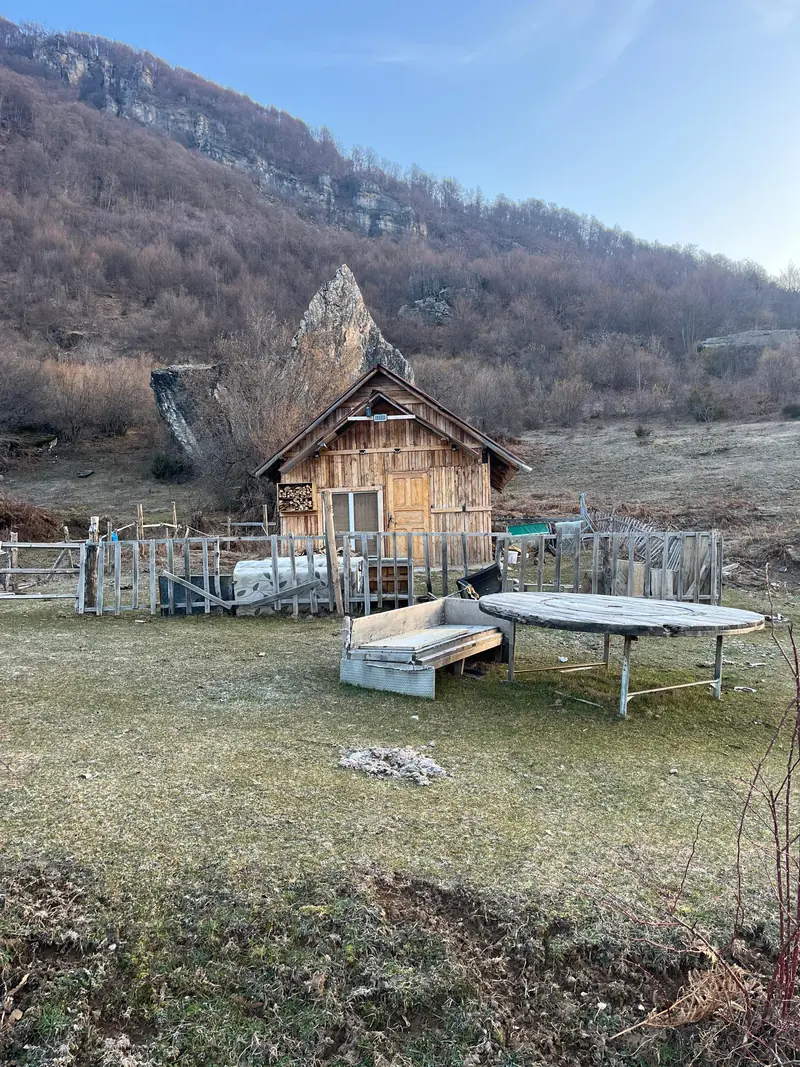 Eine Holzhütte und eine Felsnadel auf einer Bergwiese in Nordmazedonien