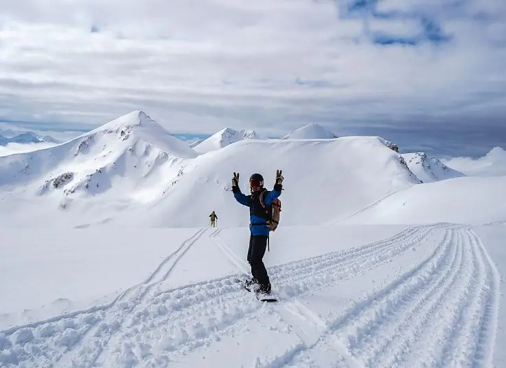 A rider celebrating on a sunny ridge with arms raised