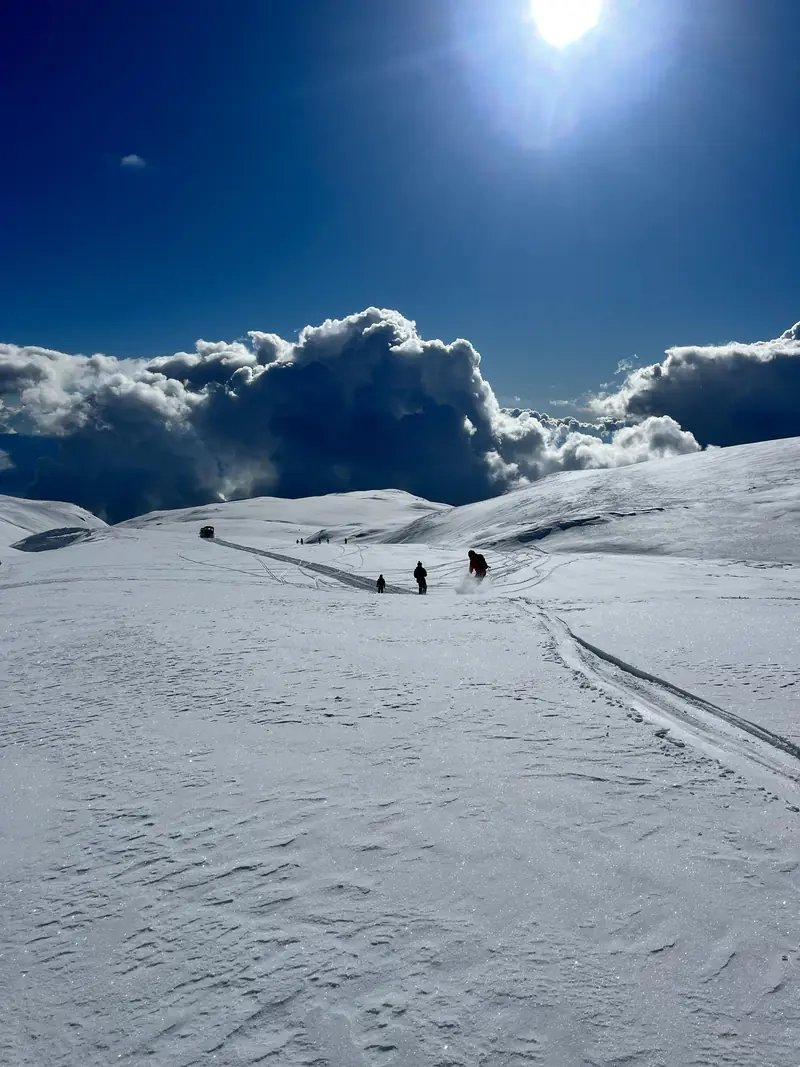 Un petit groupe en peaux de phoque sur un plateau enneigé face à une mer de nuages, en Macédoine du Nord
