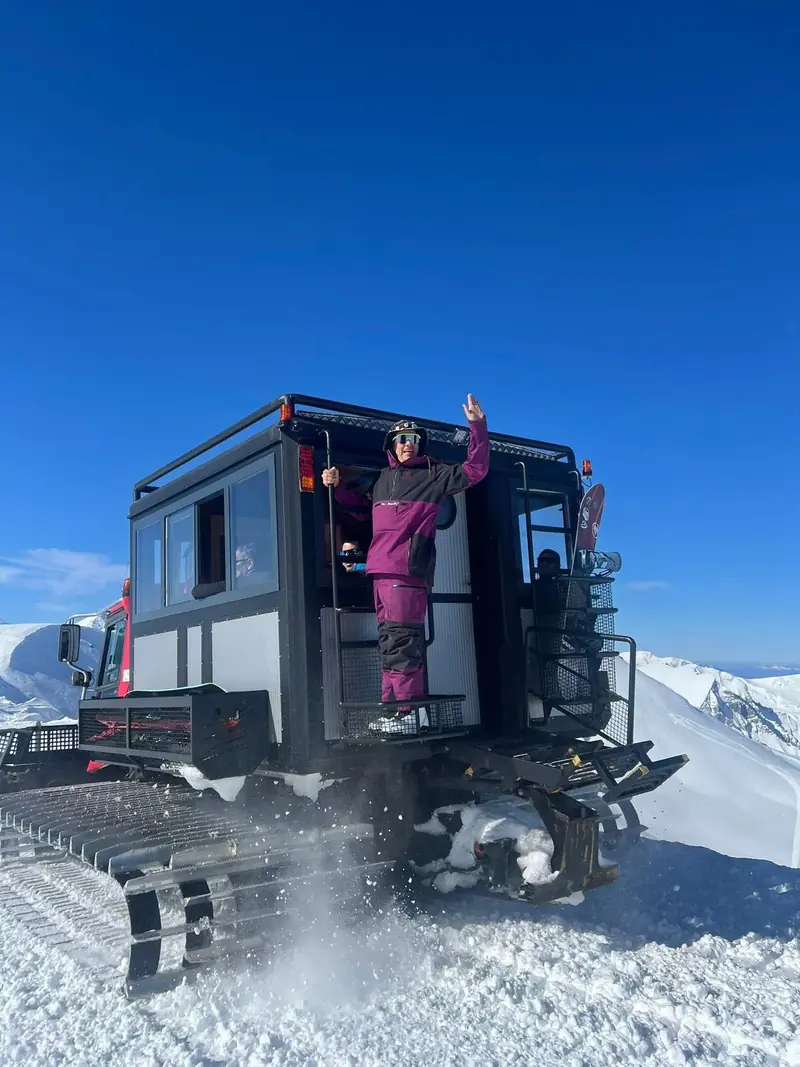 Une participante salue depuis la porte de la cabine passagers du snowcat Organix