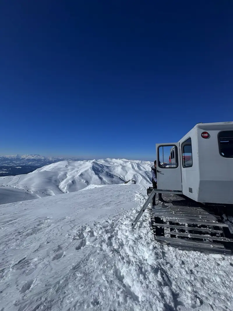 The Organix snowcat parked on a snowy ridge under a deep blue sky in North Macedonia