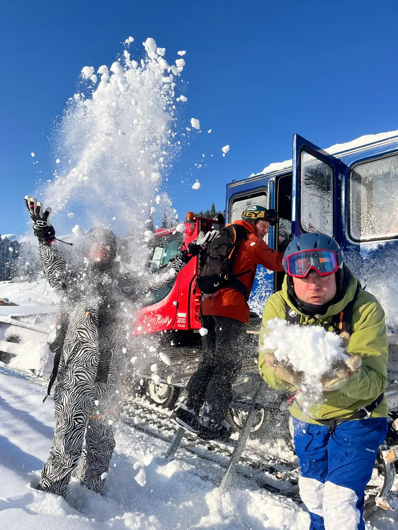 Des participants qui lancent de la neige fraîche en riant à côté du snowcat
