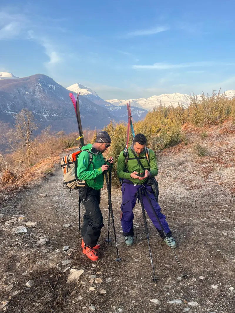 Deux randonneurs à ski, skis sur le sac, sur une colline ensoleillée au printemps