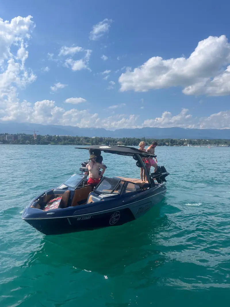 Ein Wakeboot auf türkisfarbenem Wasser mit Ridern an Bord