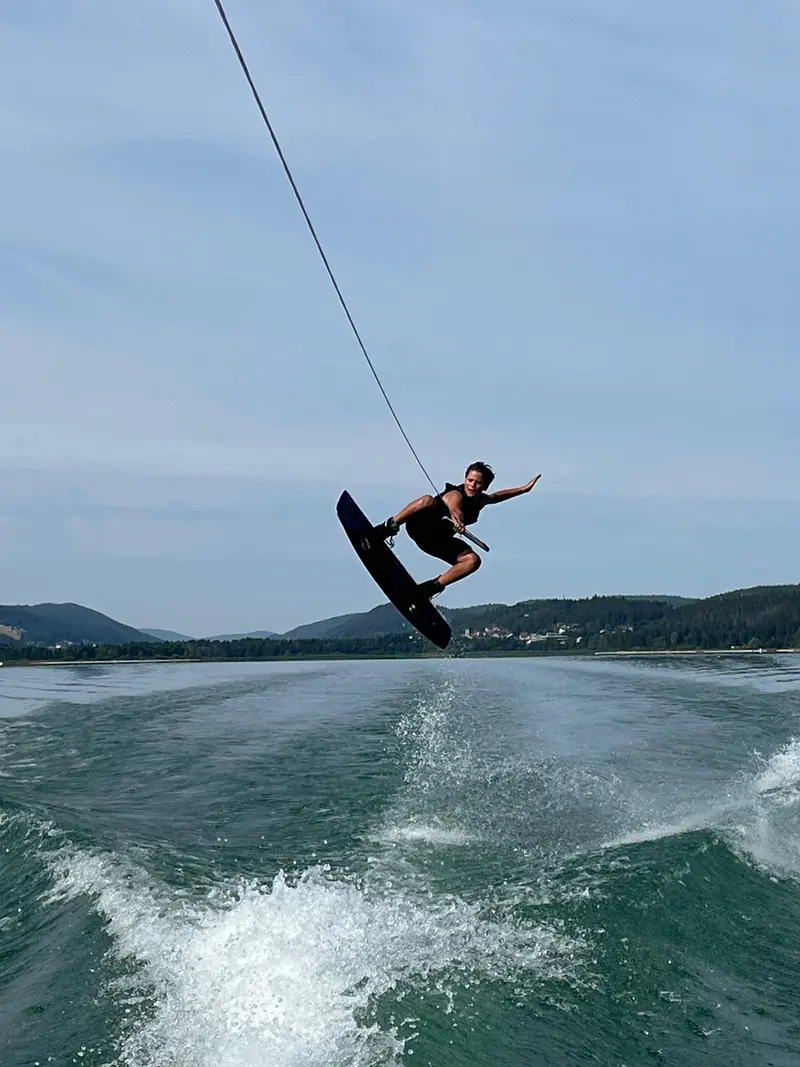 Ein Wakeboarder springt hoch hinter dem Boot